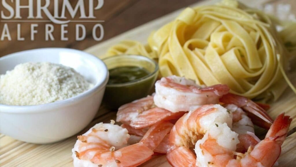Fresh shrimp, Parmesan cheese, heavy cream, and fettuccine pasta on a kitchen counter.
