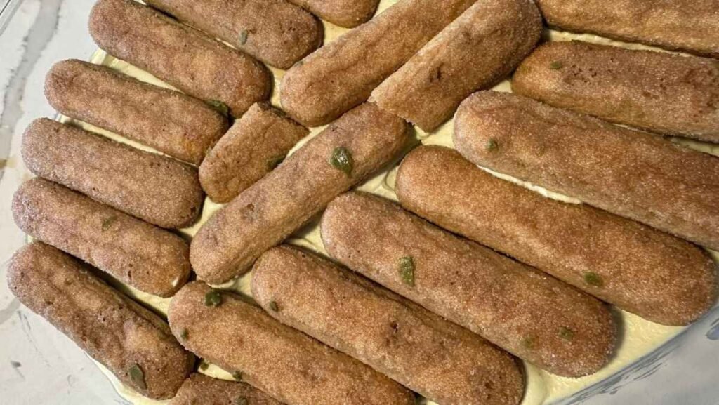Soaking ladyfingers in coffee for Pistachio Tiramisu.