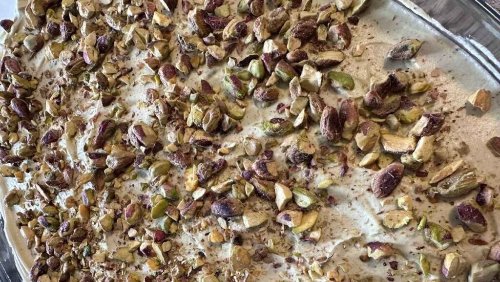Garnishing Pistachio Tiramisu with pistachios and cocoa powder